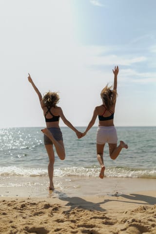 Friends jumping together on a beach during summer vacation.