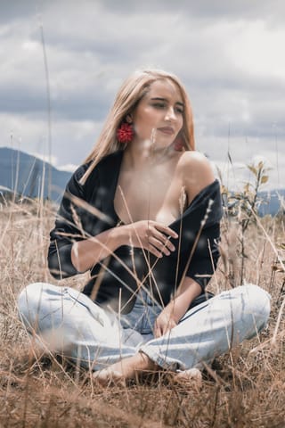 Woman sitting in a field in an outdoor portrait.