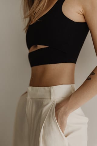 Woman in a black crop top and white pants.