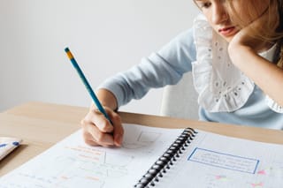 Woman drawing and taking notes at a desk.