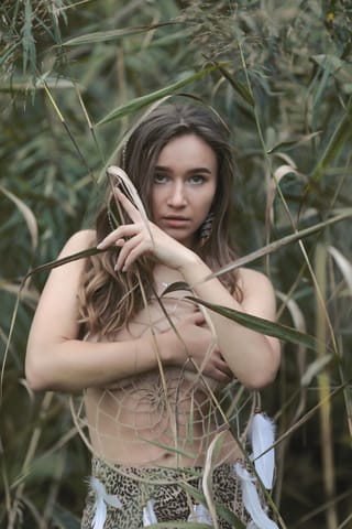 Woman standing in tall grass in a nature portrait.