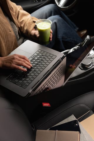 Woman working on a laptop inside a car.