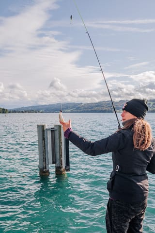 Woman fishing from a lakeside pier.