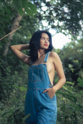 Woman in denim overalls in a forest fashion portrait.