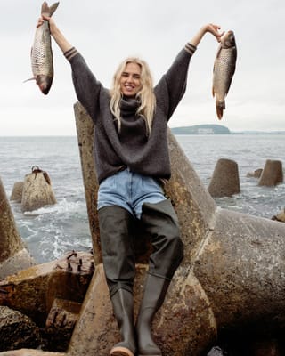 Woman holding a fresh fish by the seaside.