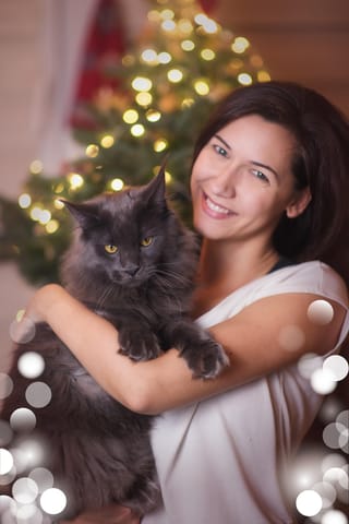 Woman holding a fluffy black cat at Christmas.