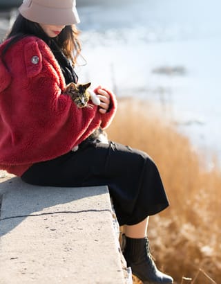 Woman sitting beside a lake outdoors.