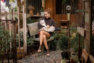 Woman holding a cat on a cozy garden patio.