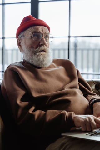 Elderly bearded man red beanie portrait.