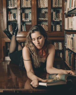 Tattooed woman reading book library lifestyle.
