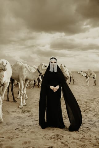 Woman black abaya camels desert travel portrait.