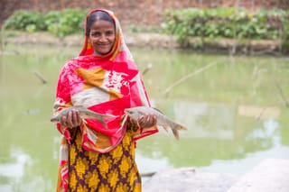 Woman holding fresh fish rural pond fishing.