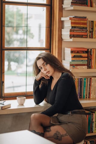 Woman library window coffee skirt tights portrait.