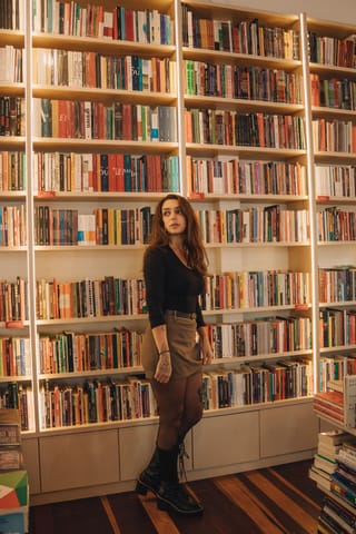 Woman standing library bookshelves casual fashion.