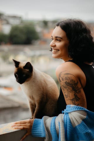 Woman with siamese cat outdoor pet portrait.